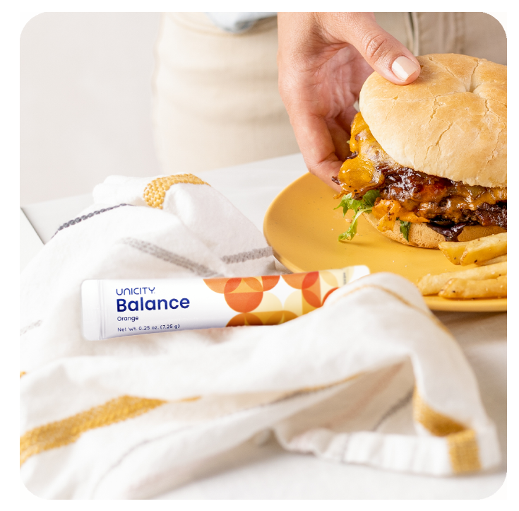 Stick Balance posé à côté d'un burger — la fibre lisse l'impact glycémique avant le repas